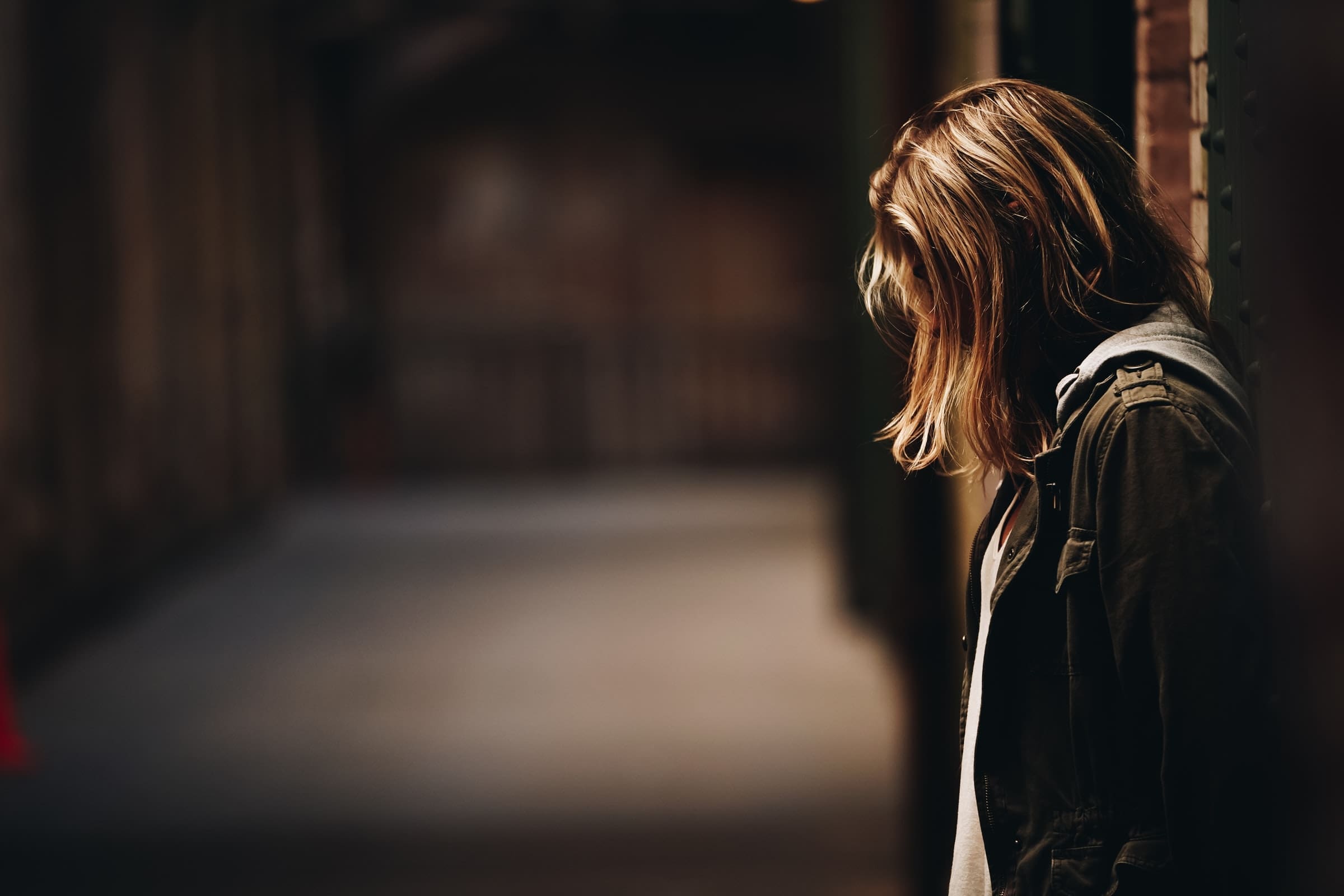 Representative photo of a woman looking dejected leaning against a pillar | Photo by Eric Ward on Unsplash