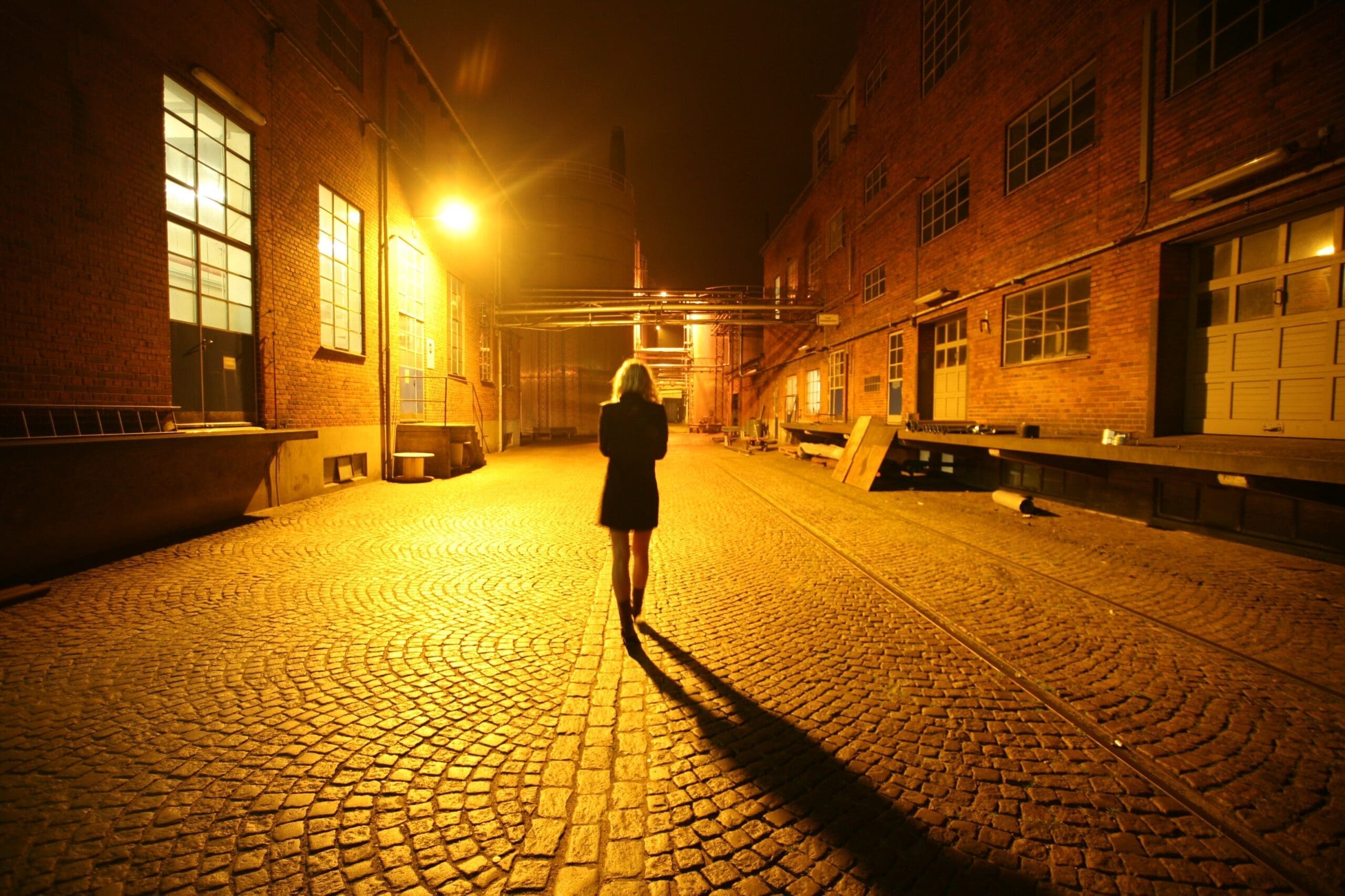 Back view of a woman walking alone on a street at night